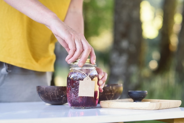 Mujer envasando una mezcla de aceites esenciales macerados para cosmética natural en el bosque.