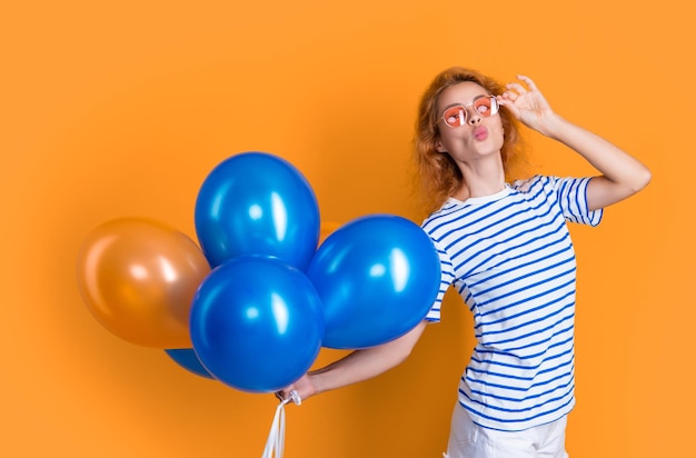 mujer envía beso con globo de cumpleaños en gafas de sol feliz cumpleaños mujer sostiene globos de fiesta en estudio mujer con globo para fiesta de cumpleaños aislado sobre fondo amarillo