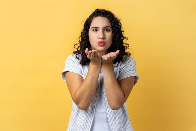 Mujer enviando un beso al aire a la cámara coqueteando y demostrando sentimientos de amor y afecto