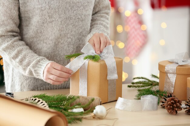 Mujer envolver regalo para Navidad en la mesa