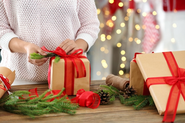 Mujer envolver regalo para Navidad en la mesa