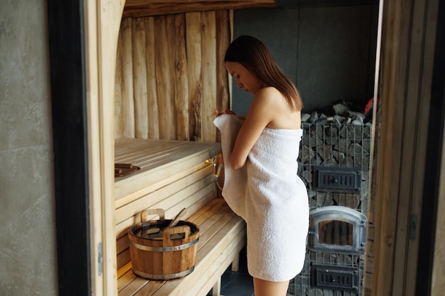 Mujer envolviéndose en una toalla en la sauna