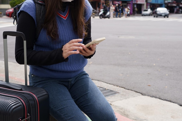 Mujer con equipaje en la calle del centro de la ciudad buscando ubicación en la aplicación de mapas en línea en un teléfono inteligente usando navegación GPS