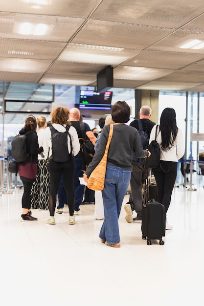 Foto mujer con equipaje de pie en una fila en el aeropuerto