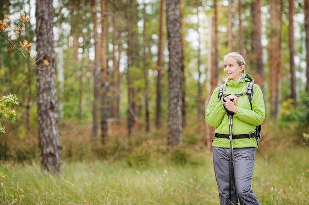 Mujer con equipo de senderismo caminando en el bosque