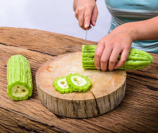 Mujer es picada una calabaza amarga en la mesa de madera