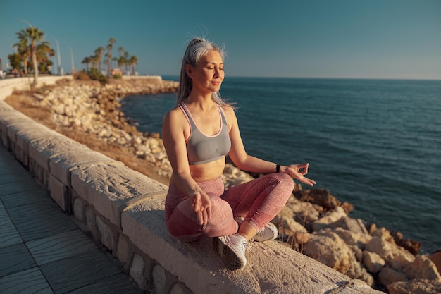 Mujer esbelta deportiva descansando junto al mar