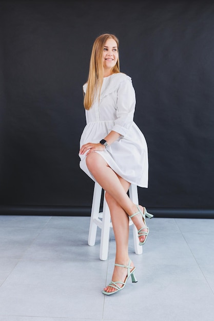 Una mujer esbelta con un vestido blanco de verano y sandalias de tacón moda  informal de verano para mujeres