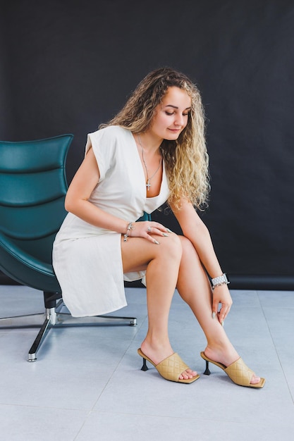 Una mujer esbelta con un vestido blanco de verano y sandalias de tacón moda  informal de verano para mujeres