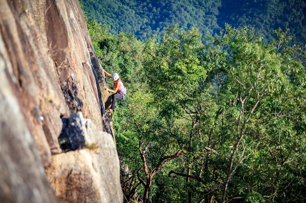Foto mujer escalando una montaña rocosa