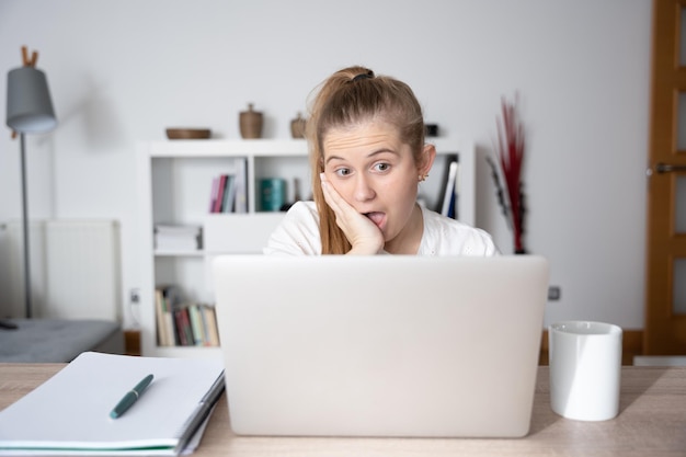 Mujer escandinava sorprendida frente a la computadora portátil