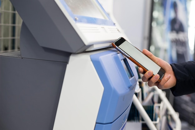 Mujer escaneando cupón de descuento en la máquina expendedora de billetes