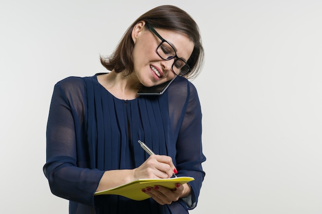 Foto la mujer escribe en el cuaderno y llamando al teléfono