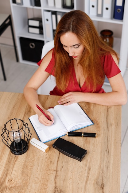 Foto mujer escribe en un cuaderno en su escritorio