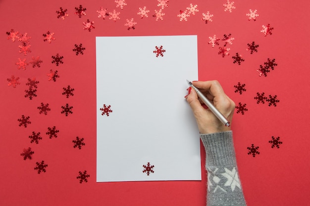 Foto la mujer escribe metas, lista de verificación, planes y sueños para año nuevo. lista de deseos para navidad en decoración roja de vacaciones.