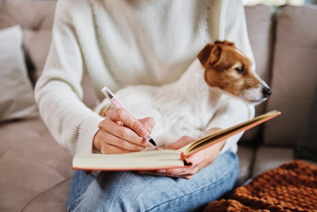 Mujer escribe notas en un cuaderno en casa