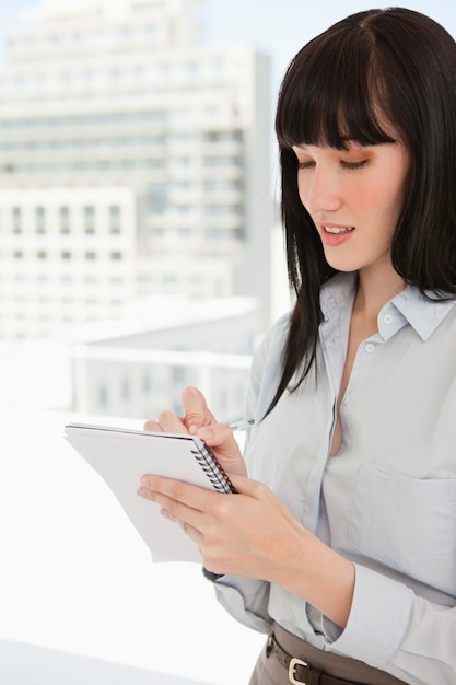 Una mujer escribiendo algunas notas en su bloc de notas