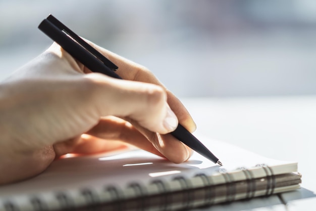 Mujer escribiendo en el bloc de notas Cerrar Centrado en una mano con bolígrafo