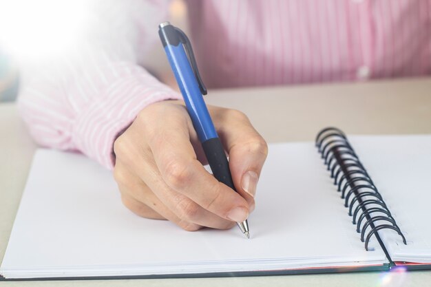 Mujer escribiendo un bolígrafo en un cuaderno