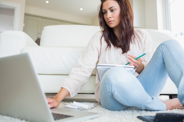 Mujer escribiendo en la computadora portátil y comparando cuentas