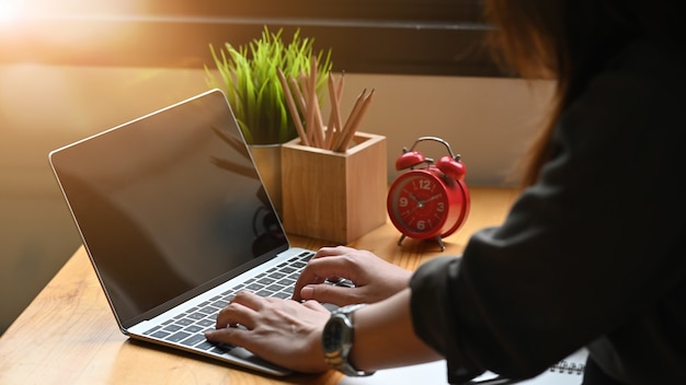 Mujer escribiendo la computadora portátil en la mesa.