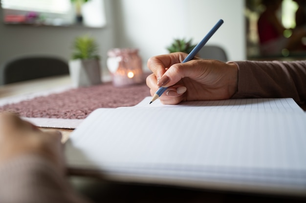 Mujer escribiendo en un cuaderno en blanco sobre un escritorio de madera