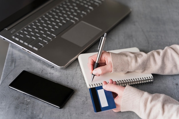 Foto mujer escribiendo en el cuaderno con computadora portátil y teléfono inteligente