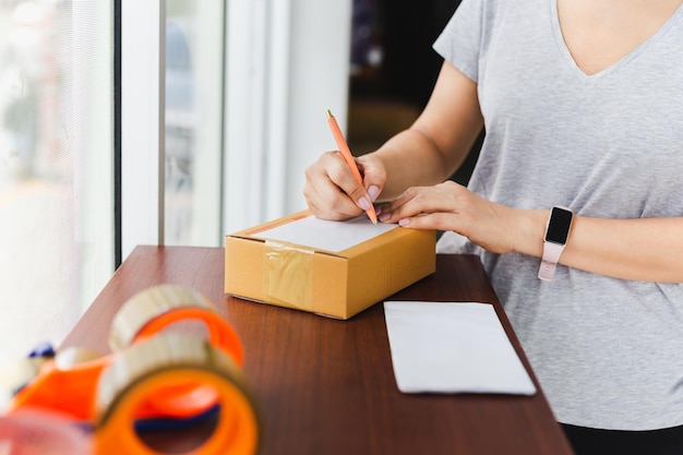 Mujer escribiendo la dirección en una caja de cartón en la oficina de correos