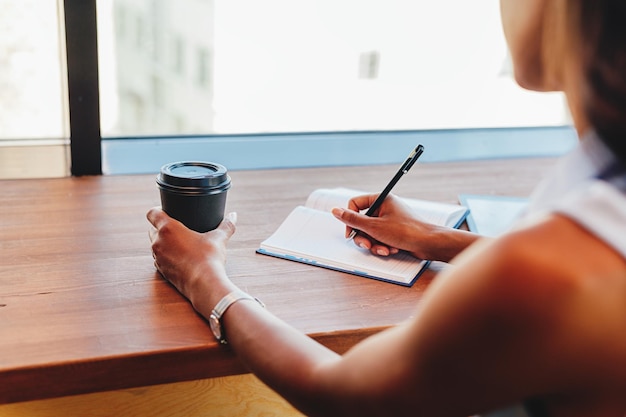 Foto mujer escribiendo en un libro en la mesa