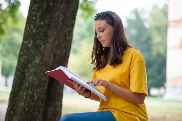 Mujer escribiendo en un libro en un parque