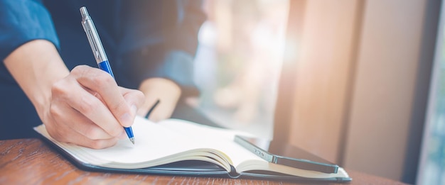 Foto mujer escribiendo a mano en un bloc de notas con un bolígrafo en el banner de officeweb