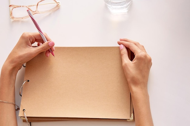 Foto la mujer está escribiendo con la mano izquierda en papel artesanal modelo de álbum concepto de zurdos internacionales