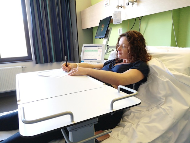 Mujer escribiendo mientras está sentada en la cama en el hospital