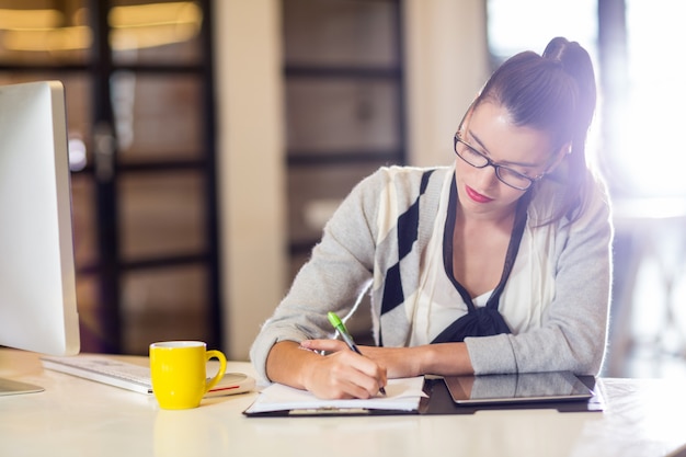 Mujer escribiendo en papel en la oficina