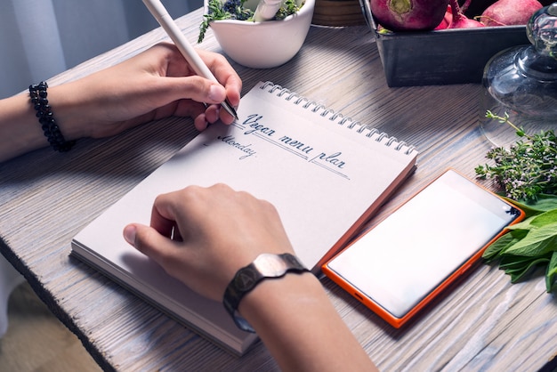 Mujer escribiendo plan de menú vegano para la semana