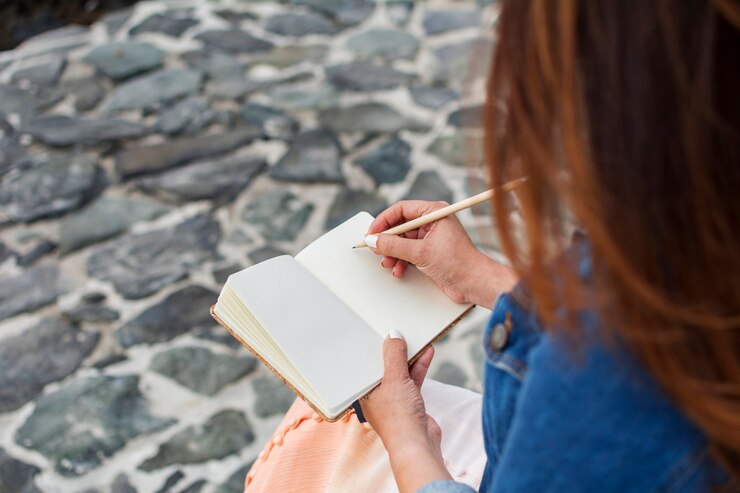Mujer escribiendo en su diario personal, al aire libre.