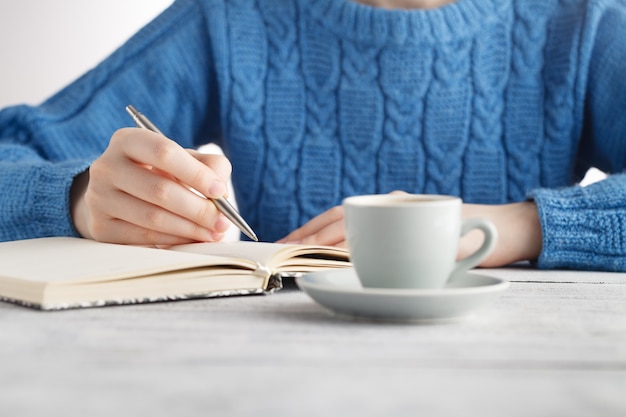 Mujer escribir en cuaderno y tomar café