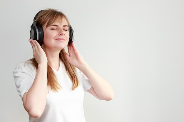 Una mujer escucha música con auriculares de fondo blanco