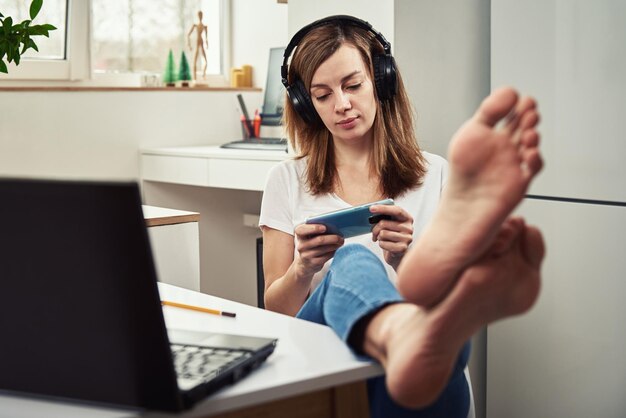 Foto mujer escuchando curso en línea en los auriculares educación a distancia freelance procrastinando