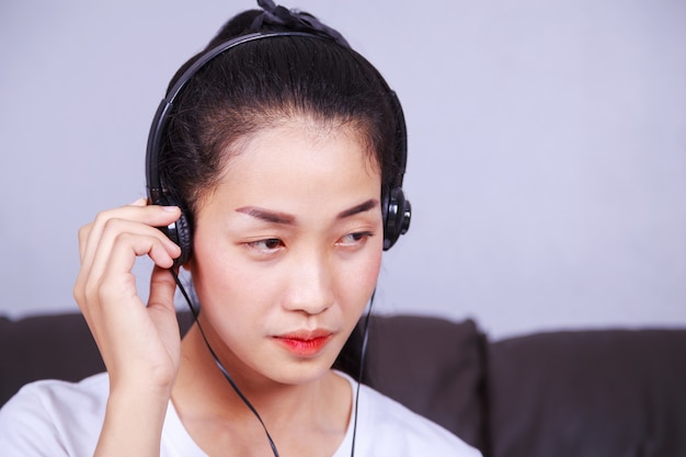 mujer escuchando música en auriculares en el sofá en casa