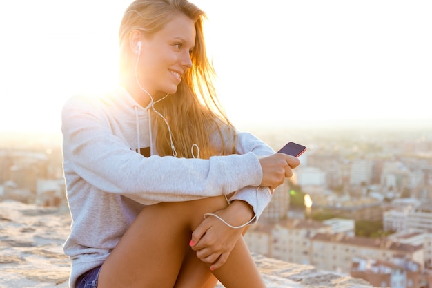 Mujer escuchando música en el borde del acantilado