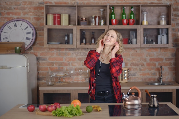 Mujer escuchando música en la cocina