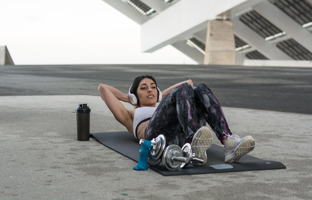Foto mujer escuchando música mientras hace ejercicio en el suelo