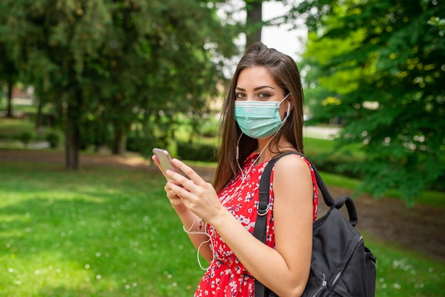 Mujer escuchando música en un parque durante la pandemia de coronavirus