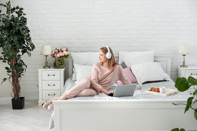 Mujer escuchando música sentada en la cama en casa
