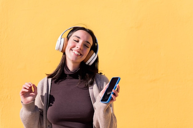 Mujer escuchando música desde el teléfono con auriculares