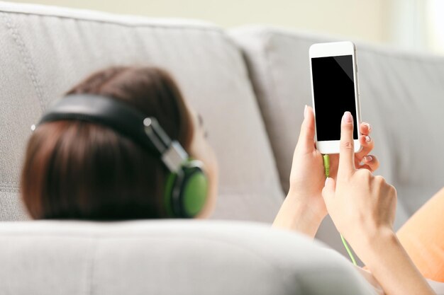 Mujer escuchando música en el teléfono inteligente en la habitación