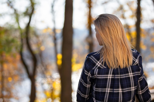 Una mujer se para con la espalda contra el fondo del otoño.