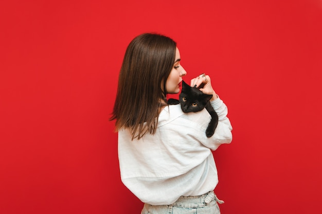 Mujer de espalda sosteniendo un gato sobre sus hombros