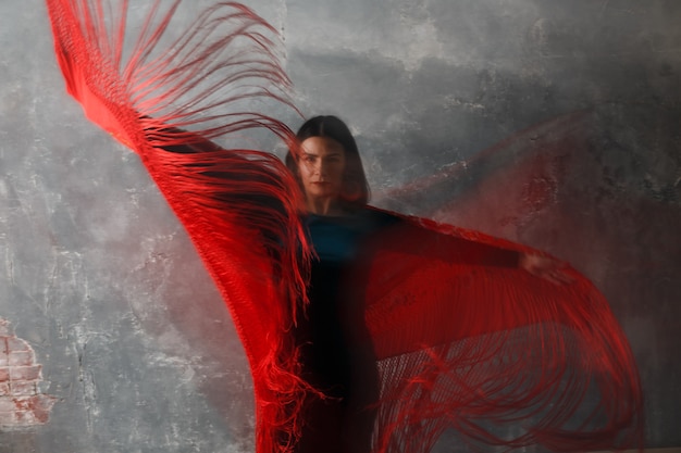 Mujer española adulta joven bailando flamenco en el desenfoque de movimiento de fondo de estudio vintage gris